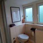 Toilette mit Duschabtrennung, Fenster und Wandbild.