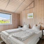 Zwei Einzelbetten in einem Holzhaus mit Fensterblick auf Grünflächen.