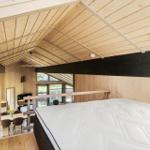 Schlafzimmer mit Bett und Blick in Wohnbereich mit Holzwand und Dach
