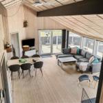 Wohn- und Essbereich mit Holzdecke, Sofa, Tisch und Stühle. Blick auf Terrasse.