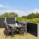 Terrasse mit Tisch und Stühlen, Blick auf grüne Bäume und Himmel.