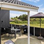 Terrasse mit Grill, Tisch, Stühlen und Sonnenschirm. Blick auf Grünfläche und Bäume.