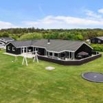 Schwarzes Haus mit großem Garten, Trampolin und Spielgeräten. Terrasse mit Sitzgelegenheiten.