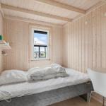 Ein Schlafzimmer mit Holzwand, Bett, Schreibtisch und Fenster.