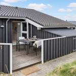 Haus mit Terrasse und Tisch. Schwarze Fassade, Holzdecke, Hausnummer 71.