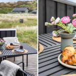 Terrasse mit Tisch, Stühlen und Frühstück. Hintergrund: Grasland und Häuser.