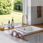 Küchenarbeitsfläche mit Waschbecken und Fensterblick auf Grünfläche.