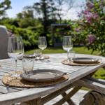 Rundtisch mit Tellern und Gläsern im Garten mit Blumen und Grün.