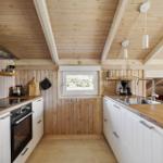 Küche mit Holzwand, weißen Schränken und Holz Arbeitsplatte.