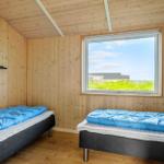 Zwei Betten mit blauen Decken. Holzwände und ein Fenster mit Blick auf Gras und Himmel.