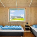 Zwei Betten mit blauen Decken, Holzwände und Fensterblick auf Grünland.