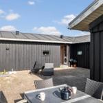 Hinterhof mit Sitzgelegenheiten und Waschmaschine. Schwarze Holzwände und Terrassenbereich.