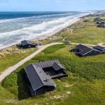 Aerielansicht von Strandhäusern mit Grünflächen und Meer im Hintergrund.
