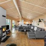 Wohnzimmer mit Kamin, Sofa und Essbereich unter Holzdecke.