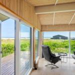 Terrasse mit zwei schwarzen Sesseln und Blick auf Grasland und Strand.