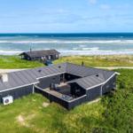 Moderne Strandhaus mit Terrasse und Meerblick. Umgeben von Gras und Dünen.