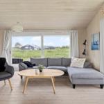 Wohnzimmer mit grauem Sofa, runden Tisch und Blick auf Grünland.