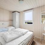 Schlafzimmer mit Bett, Kleiderschrank, Spiegel und Stuhl an Holzwand.