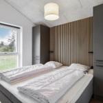 Schlafzimmer mit Doppelbett, Fenster und Holzwand. Zwei Schränke und Deckenleuchte.