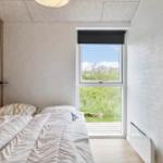 Schlafzimmer mit Bett, Fenster und Holzwand