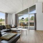 Wohnzimmer mit Ledersofa, Glasfront und Holzboden. Fernseher an Ziegelwand.