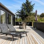 Terrasse mit Liegen, Tisch und Stühlen. Hintergrund: Baum und Himmel.