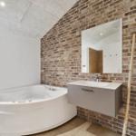 Bad mit Whirlpool, Backsteinwand, Spiegelschrank und Bambusleiter