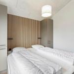 Schlafzimmer mit Doppelbett, Holzpaneelen und integrierten Schränken.
