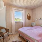 Schlafzimmer mit Bett, Stuhl und Fenster mit Blick auf Grün.