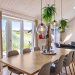 Essbereich mit Holztisch, Stühlen und Pflanzen. Durchgang zur Lounge mit Sofa und Fenster.