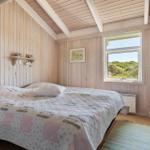 Schlafzimmer mit Holzwand und Fensterblick auf Grünflächen