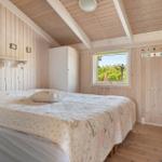 Schlafzimmer mit Bett, Kleiderhaken und Fenster zum Garten.