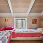 Zimmer mit zwei Betten, Holzwandverkleidung und Fenster mit Gitter.