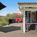 Terrasse mit Tisch, Stühlen und Grill unter schwarzem Sonnenschirm. Daneben Flagge und Pflanzen.