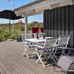 Terrasse mit Tisch, Stühlen und Sonnenschirm. Blick auf Grünland und Flagge.