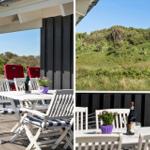 Terrasse mit Tisch, Stühlen und Blick auf grüne Hügel. Daneben hängt eine dänische Flagge.