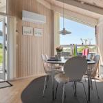 Essbereich mit Tisch, Stühlen und Blick auf Balkon. Holzwände und große Fenster.