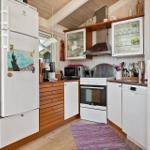 Küche mit Kühlschrank, Herd und Spülmaschine. Holzoberflächen und Glasregale.