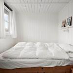 Ein Schlafzimmer mit weißer Wandverkleidung, einem Bett und einem Fenster.
