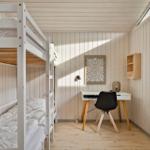 Zimmer mit Doppelstockbett, Schreibtisch und Fenster.
