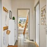 Flur mit Holzwand, Garderobe und Blick in Wohnbereich mit Treppe.