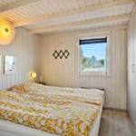 Schlafzimmer mit Bett, Fenster und Holzwandverkleidung.