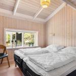 Schlafzimmer mit Holzwand, Bett und Fenster zum Garten.
