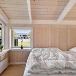 Schlafzimmer mit Holzwänden, Bett und Fenstern mit Blick nach draußen.
