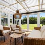 Terrasse mit Sitzgruppe, Tischen und Decke. Blick auf Garten und Haus.