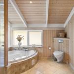 Bad mit Whirlpool, Toilette und Holzwandverkleidung. Fenster mit Blumenvase.