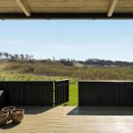 Terrasse mit Holzdecke und Blick auf grüne Wiesen und Bäume.