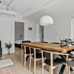 Essbereich mit Holztisch, Stühlen und Kaminofen. Durchgang zu Schlafzimmer.