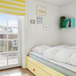 Bedroom with bed, windows, and door. Wall with pictures and green shelf.