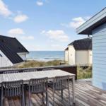 Deck with table and chairs offers view of sea and beach houses.